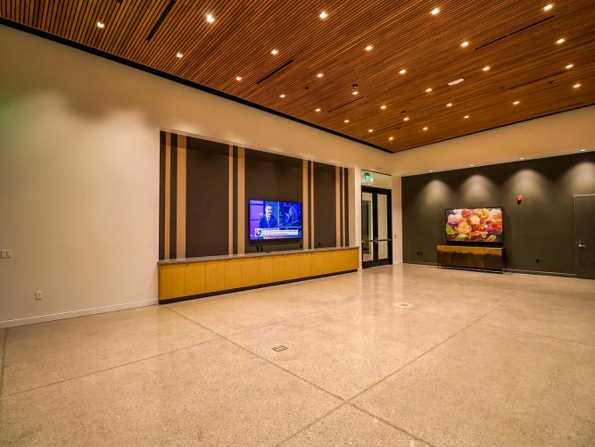 Large empty modern room with polished concrete floors and a wood-slat ceiling