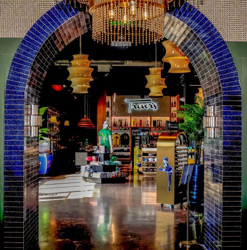 A framed view of the retail shop through a large blue-tiled archway with a crystal chandelier above.
