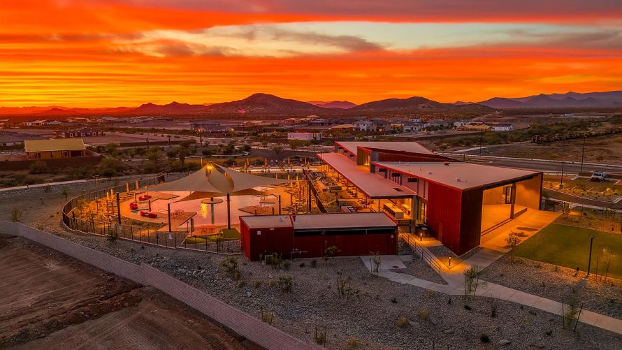 High-angle view of a desert community center and pool under an orange sunset