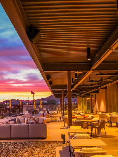 Expansive covered outdoor patio with lounge seating and dining tables at sunset