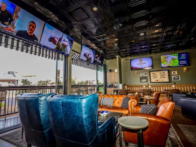 View from inside a lounge area looking out onto a sunny patio through large open glass doors.