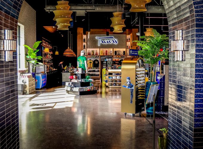 View through a tiled archway into the main retail space featuring a neon sign and merchandise displays.