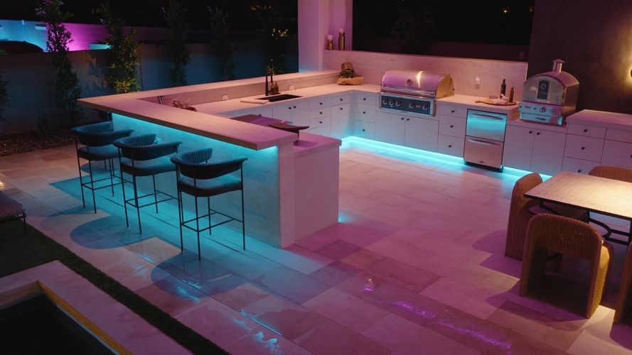 Outdoor bar and grill area with bright teal LED perimeter lighting