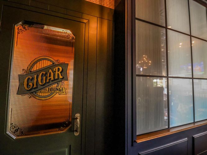 Close-up of a frosted glass door with Cigar Lounge etched in gold lettering.