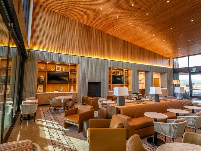 Spacious clubhouse lounge with wood-slat ceilings, leather chairs, and warm lighting