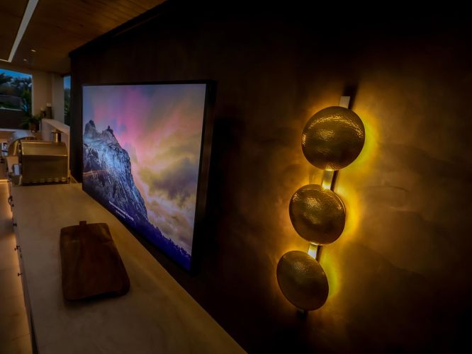 Close-up of a vertical wall light with three hammered gold circular shades