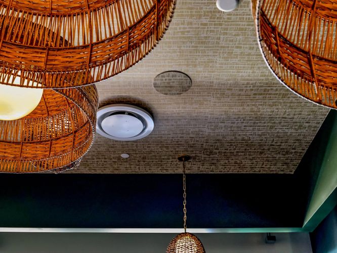 Looking up at woven basket light fixtures against a patterned ceiling.