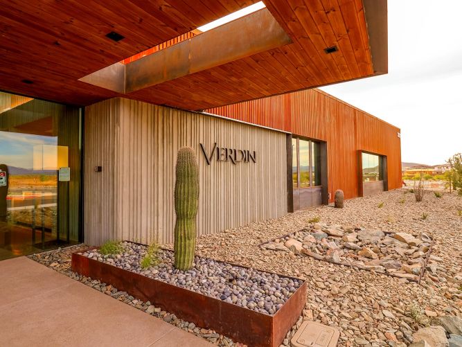 Modern concrete building entrance featuring a tall cactus and rock landscaping