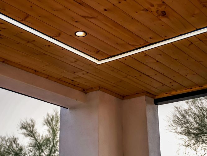 Low angle shot of a wood plank ceiling with a recessed light and linear glow