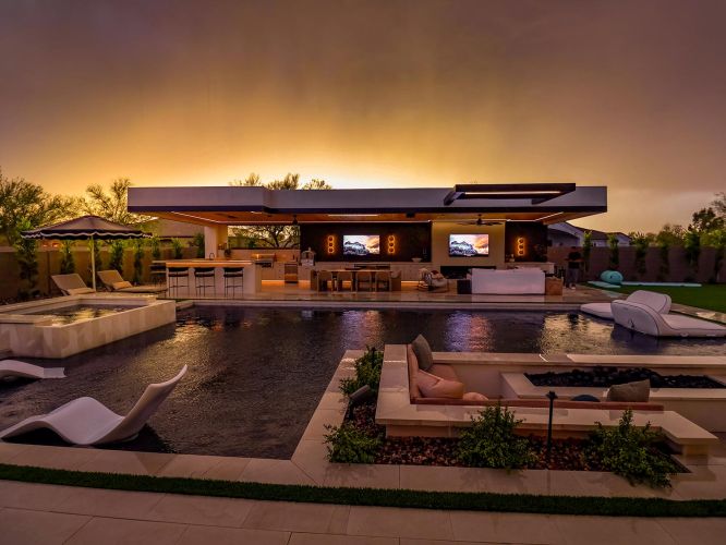 Expansive backyard pool area with a sunken fire pit and modern outdoor pavilion at sunset