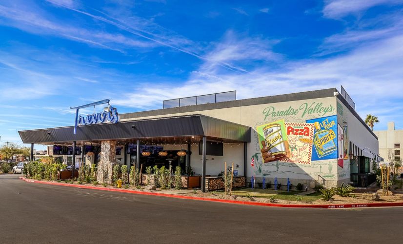 Wide exterior view of the building featuring a colorful mural with Paradise Valley and retro-style beverage art.