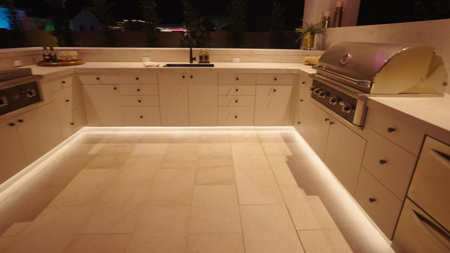 Close up of white outdoor cabinetry with warm under-cabinet lighting
