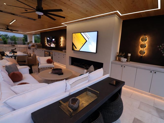 Luxury outdoor living room with white sofas and a large television above a fireplace