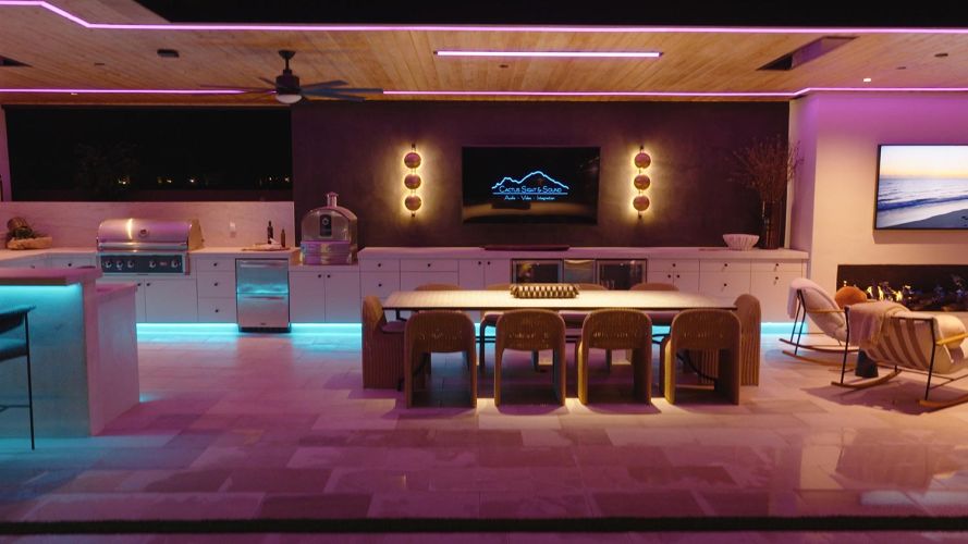 Outdoor kitchen and dining area with glowing teal under-counter lights