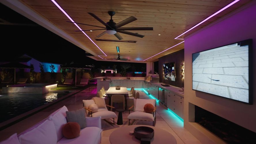 Modern outdoor lounge with white chairs and fireplace under a wood ceiling