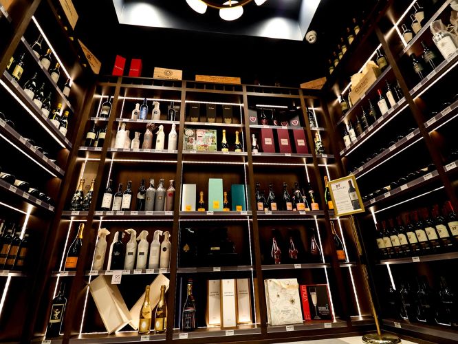 Close-up of a high-end wine cellar featuring backlit shelves and premium bottles of champagne and wine.