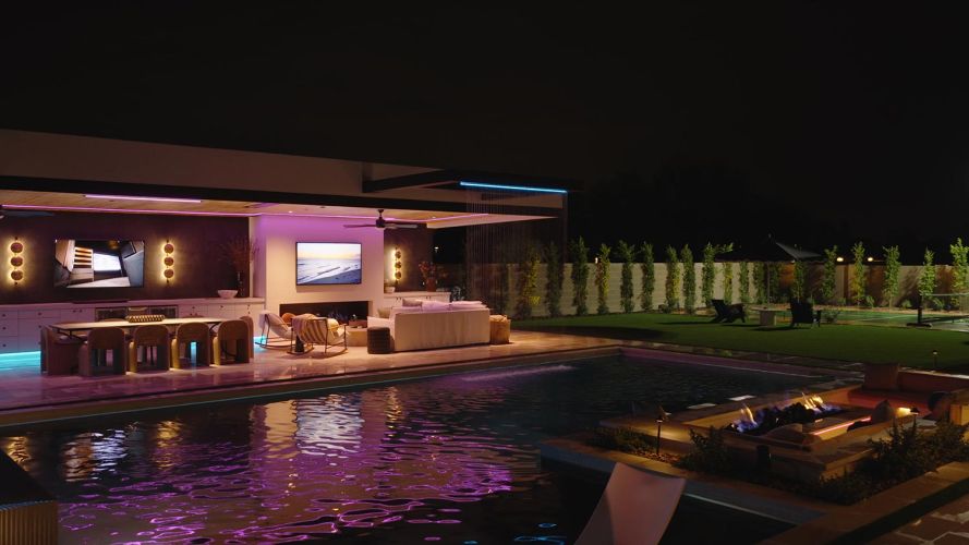 Luxury backyard patio at night with pool and purple accent lighting
