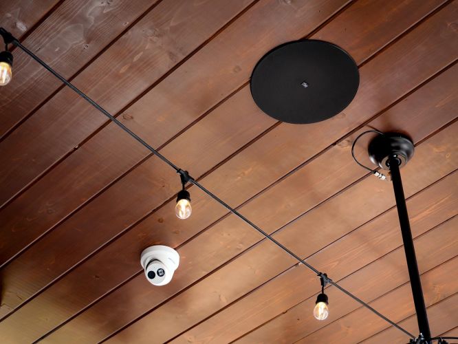 Wooden ceiling details featuring string lights, a circular speaker, and a security camera.