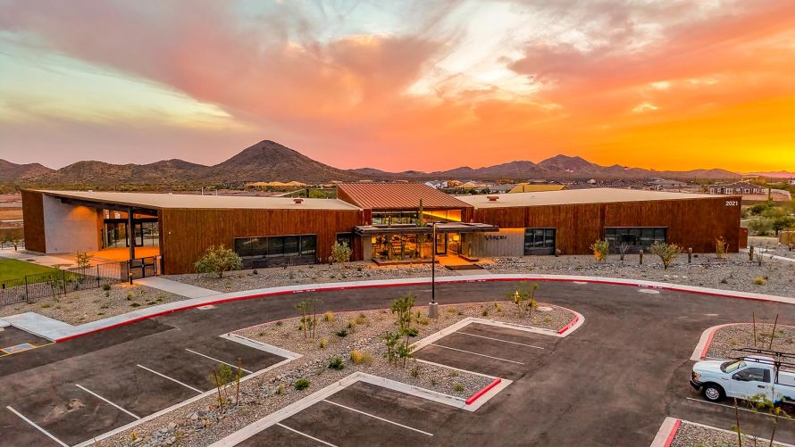 Modern desert building exterior with a parking lot under a vibrant sunset sky