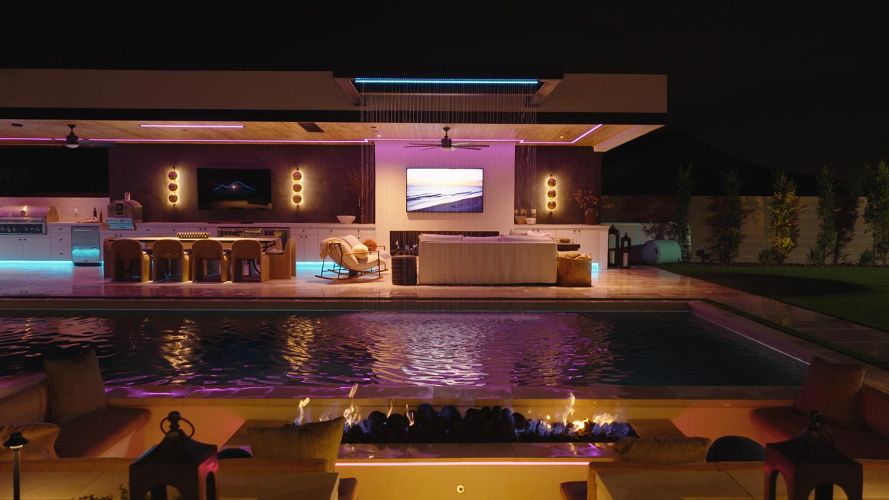 Backyard fire pit and pool area with vibrant purple and blue lighting