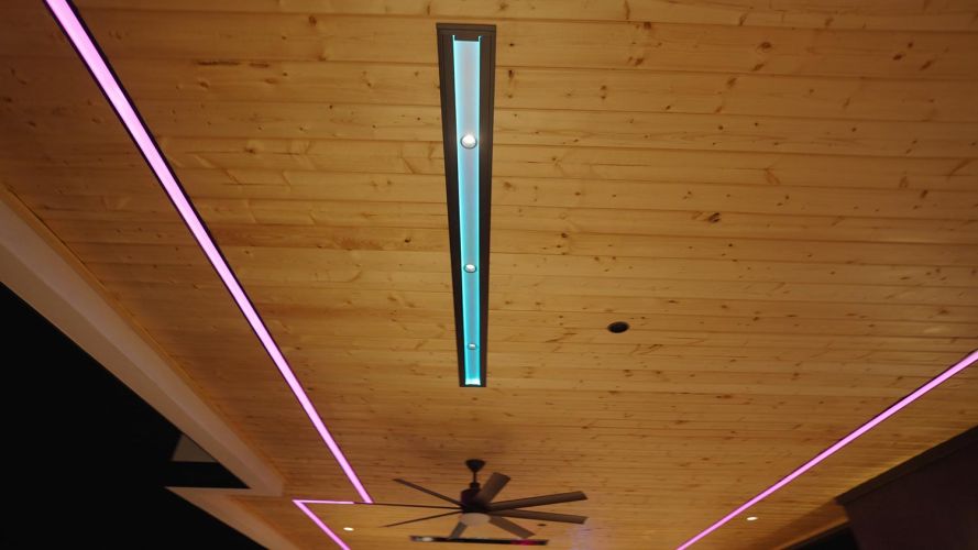 Wooden ceiling with embedded pink and blue linear light strips