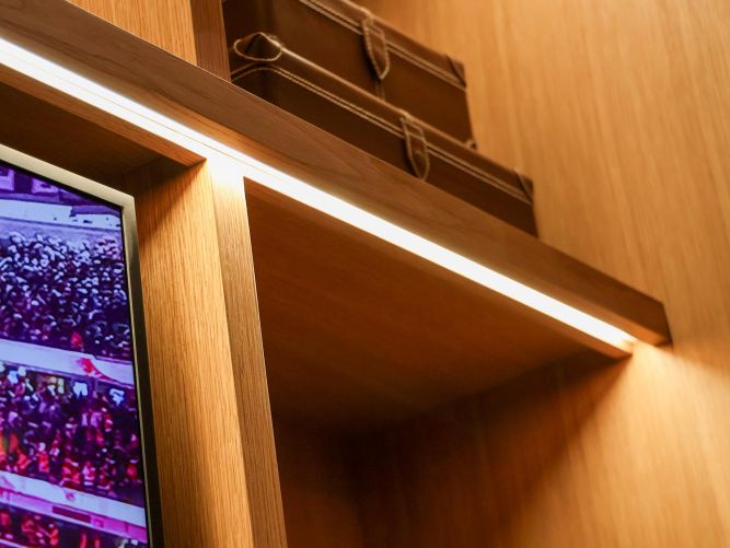 Close-up of a wooden shelf with integrated LED lighting holding a vintage suitcase