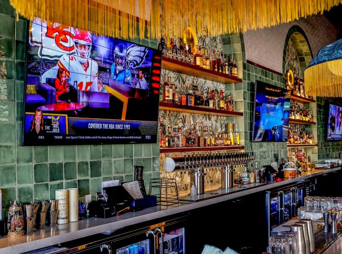 View of the bar area featuring a long row of beer taps and a TV showing a football game.