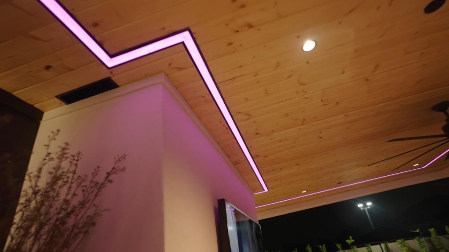 Angled view of a wood plank ceiling with zig-zag pink light strip