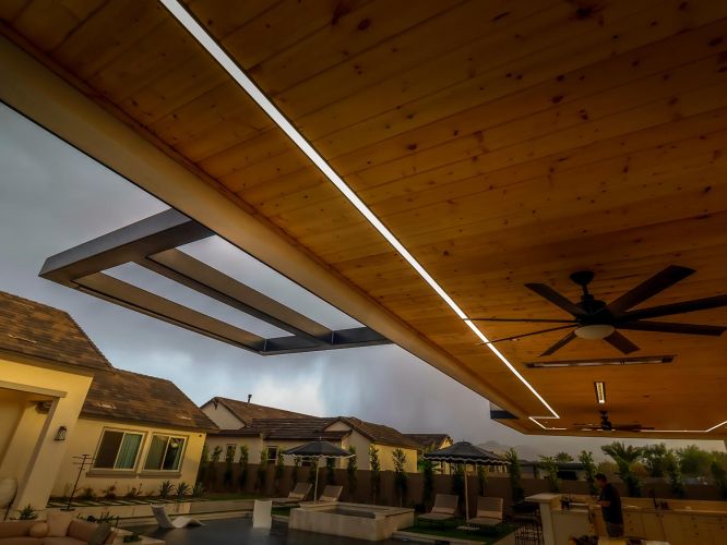 Covered patio with wood ceiling and linear lights overlooking a backyard
